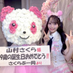 SKE48の山村さくらさん。19歳の生誕祭でファンから贈られたパンダ型のフラワースタンドの横で、お揃いのパンダ耳カチューシャをつけて笑顔でピースサインをしている。